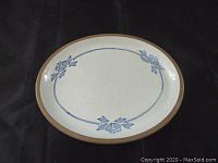 Top view of the oval ceramic platter showing blue leaf decorative pattern and brown rim