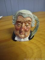 Front view of Royal Doulton Toby mug "The Lawyer" depicting a lawyer's facial features with powdered wig and formal attire.