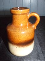 Photo of a 6 inch pottery jug with brown to beige coloration and a handle. Bottom embossing indicates W. Germany 414-15.