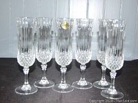 Six clear lead crystal champagne flutes standing upright, showing the vertical faceted cut design and decorative base