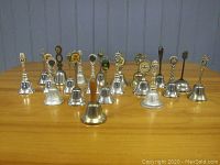 Full set of 20 souvenir bells arranged in rows, showing various decorative handles and bell shapes