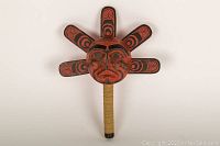 Front overall view of carved wooden Haida-style rattle showing central face and radiating paddles