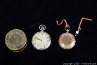 Full view of American Waltham Watch Co. metal case, WWII Cyma pocket watch, and unknown pocket watch with pink strap.