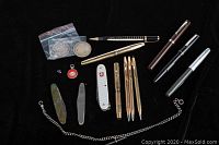 Overhead view of full lot on black background: pens, coins, knives, chain, knife, gem, fob