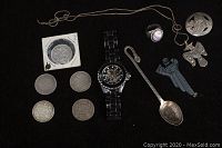 Full lot arranged on black background showing watch, coins, ring, pendants, spoon