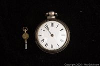 Front view of silver pocket watch with key, white dial with Roman numerals, black hands, watch in closed position.
