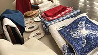 Full view of folded tablecloths, quilted covers, plates and coasters on table