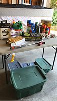 Full view of lawn and garden care products on a table and stacked storage bins below