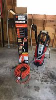 Pressure washer unit, edger in box, extension cord on concrete floor