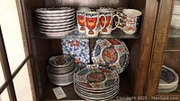 Various pieces stacked on cabinetry shelves showing dinner plates, salad plates, bowls, mugs, teacups