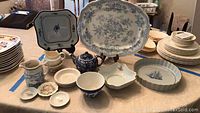 Photo showing assorted English and French china items on a table including bowls, platters, teapot, creamer, and plates.