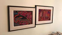 Both framed textiles hung side by side on wall