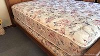 Side view showing mattress atop the boxspring on a bed frame, floral pattern clearly visible.