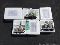 Five Thomas Kinkade Winter Wonderland Illuminated Garland buildings in their original Styrofoam boxes with certificates, set outdoors.