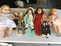 Overview photo of all dolls laid on table showing various sizes and types including roller skate dolls and porcelain figures.