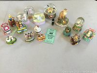 Photo of full lot showing grouped snow globes and hinged trinket boxes on white surface