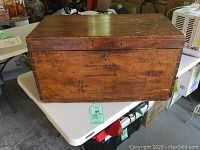 Front view of rustic wooden trunk showing hinged top and wood surface with scuffs and scratches