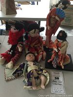 Five Asian dolls on the floor showing variety of materials and traditional attire.