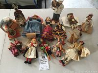 Overview of various international dolls arranged on a table, showing assortment of cloth and painted dolls from multiple countries.