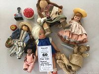Lot of six assorted vintage dolls with some accessories on beige surface