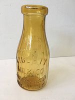 Front view of the amber glass milk bottle showing the embossed Liberty Milk Co. name and company information.
