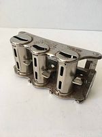 Front angled view of the vintage metal coin change holder showing three cylindrical coin slots with levers and visible wear.