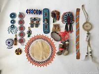 Full view of 17 vintage First Nations leather and beaded pieces arranged on white surface.