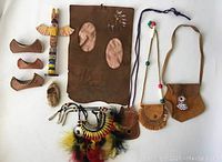 Full lot view of all 10 First Nations themed leather and beaded items including moccasins, pouches, necklaces, and wooden totem pole figurine.