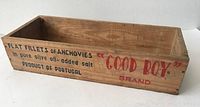 Wide view of the wooden box showing text 'FLAT FILLETS of ANCHOVIES in pure olive oil - added salt PRODUCT OF PORTUGAL' on one side and 'GOOD BOY BRAND' on another side.