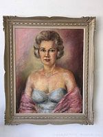 Full view of the framed portrait painting showing the woman in a light blue dress and pink shawl, with the beige carved frame visible.