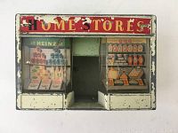 Front view of the metal 'Home Stores' shop front showing colorful printed advertisements and shop entrance.