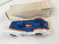 Photo of vintage blue, white, and orange Cox Canam Manta slot car with original box in background