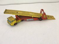 Full side view of the yellow and red metal car transporter toy with two ramps and 'DAF' markings on the side.