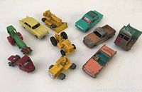 Top view of all 10 vintage Lesney toy vehicles arranged together on a white surface showing condition and color.
