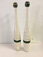 Pair of vintage wooden Indian clubs standing upright, showing full length and paint wear