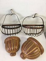 Photo showing two metal hanging plant holders with wooden slats and two brown pottery wall-mounted plant holders.