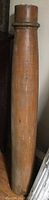 Side view showing the tall wooden pillar's smooth cylindrical form and natural wood grain with minor scuffs and dents.