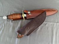 Two knives with their sheaths laid side by side on gray background