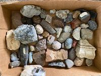 Cardboard box containing assortment of rough stones and polished rocks