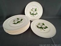 Nine 10-inch dinner plates and four 9-inch salad plates stacked and displayed, showing magnolia print with gold rim.