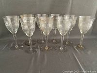 Set of nine crystal wine glasses displayed together on a gray surface.