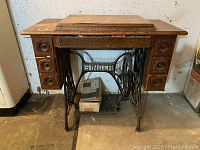 Full view of oak cabinet with cast iron treadle base and drawer banks