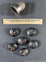 Group photo showing six handmade silver buttons arranged with a metal thimble and information tag describing the buttons as genuine Reservation Indian handmade from solid coin silver slugs.