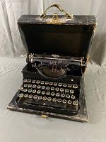 Vintage Royal typewriter situated inside an open black fixed case with handle, showing the keyboard and carriage.