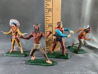 Front view of all four figurines against ruler backdrop showing height and details