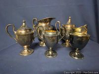 Vintage silver set with six pieces on display against a dark background to show the whole collection