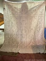 Full view of vintage hand embroidered quilt hanging, showing multiple signature panels and overall design.