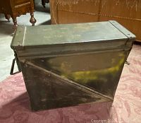 Side view of the green metal ammunition box with handle and visible wear