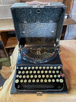 Open view of black Remington typewriter inside case showing keyboard and carrying case interior lining