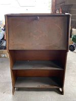Front view of antique writing desk closed with visible scratches and wear on the drop-down top.